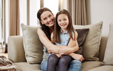 Obraz premium Mom, girl and hug on sofa for portrait with smile, bonding and relax in living room for connection in home. People, mother and daughter on couch, happy or relationship at family house in Australia