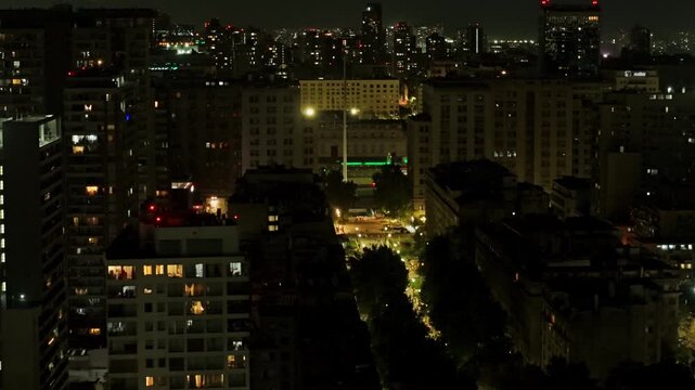 Nighttime telephoto aerial view of Paseo Bulnes towards La Moneda Presidential Palace, Santiago, Chile. People walking.