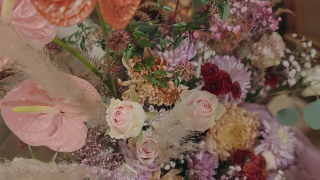 Close view of pastel bouquet with pink anthuriums roses chrysanthemums dried textures and greenery