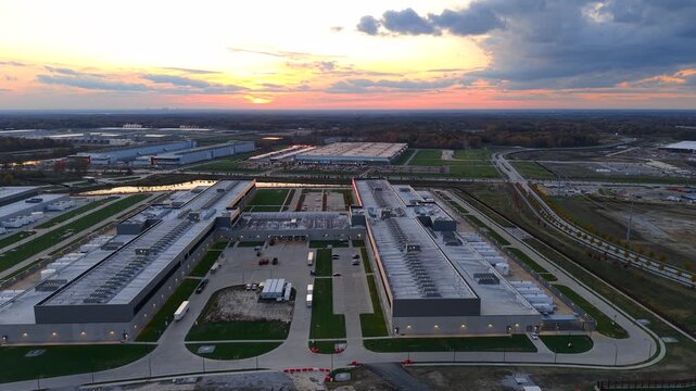 Expansive aerial view orbiting around a large, modern data center complex at sunset