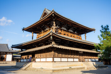 Side view of the Main Hall (Kondo) at Horyuji Temple in Nara, Japan, bathed in warm golden hour light under a clear blue sky, emphasizing the historic wooden structure, Japanese architecture