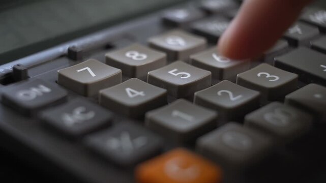 Close-up view of a finger pressing buttons on a vintage calculator showcasing retro office technology