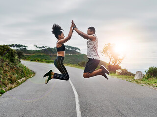 Fototapeta premium Runner, personal trainer and high five with couple outdoor for fitness club, health and workout partner. Coaching, exercise training and support with man and woman in road for jump, target and energy