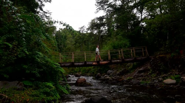 Woman Crossing On Wooden Bridge At Salto Las Cascadas Near Puerto Octay, Los Lagos Region, Chile. Static Shot