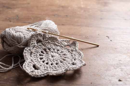 Crochet motifs and hook on a wooden table