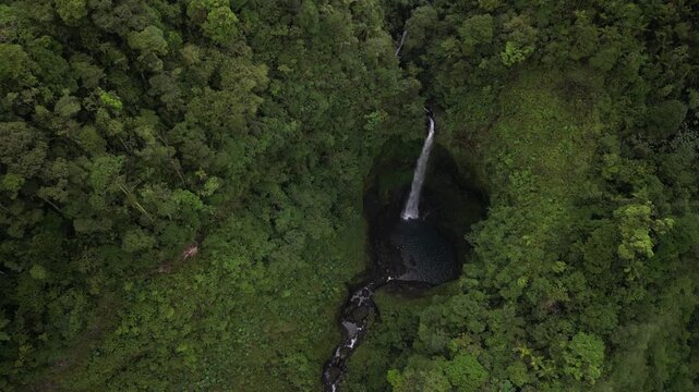 Quebrada Gata aerial tilt up on waterfall on Rio Toro in Costa Rica rainforest in lush green jungle landscape
