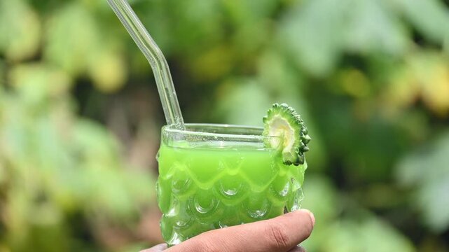 Bitter gourd or bitter melon juice on a blurry green background. This emerald tonic is celebrated in traditional medicine for its ability to regulate blood sugar and detoxify the body.
