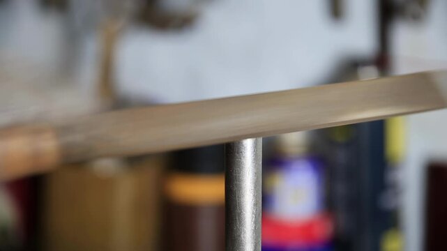 Detailed close-up footage of worker using metal file on end of steel pipe, creating beveled edge. Manual labor activity shaping metal part for fabrication and construction. Precision work on metal obj