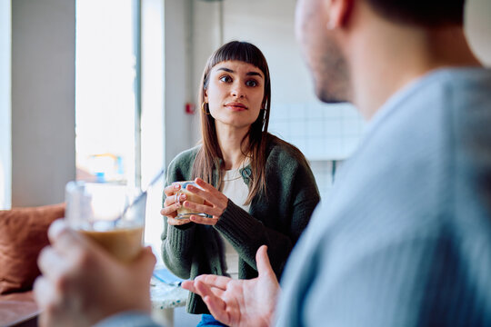 Woman and man having a conversation in a coffee shop, engaging in effective communication and active listening over coffee