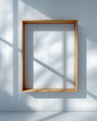 Minimalist empty wooden picture frame casting soft shadows on a light wall