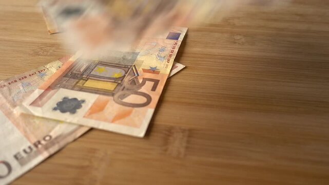 50 Euros notes falling onto a wooden background