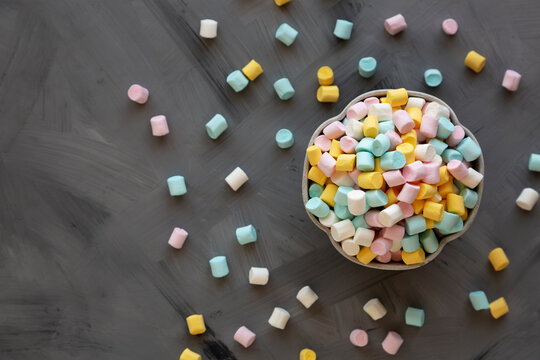 Unhealthy multi-colored mini marshmallows in a bowl, top view.