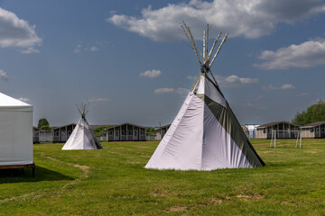 Beautiful view of few summer camping tipi in field. Tee pee built on green grass. Traditional teepee tent wigwam located in nature © Lyudmila