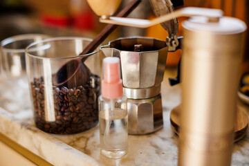 Ingredients for making coffee. Moka pot, bean spray, coffee grinder with coffee beans standing on the kitchen table.