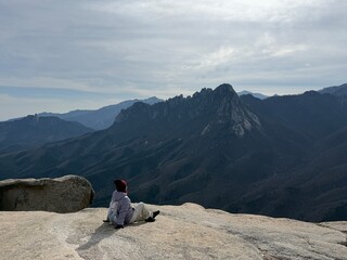 A traveler sitting on a mountain summit and enjoying the majestic rocky mountain view