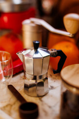 Moka pot on the table at home. Coffee making concept.  Moka pot, bean spray, coffee grinder, jar of coffee beans standing on the kitchen table.