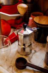 Ingredients for making coffee. Moka pot, bean spray, coffee grinder with coffee beans standing on the kitchen table.