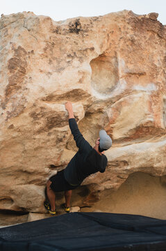 Climber assessing next hold while bouldering in Joshua Tree desert