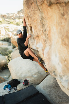 Young climber scaling granite boulder in Joshua Tree desert outdoors