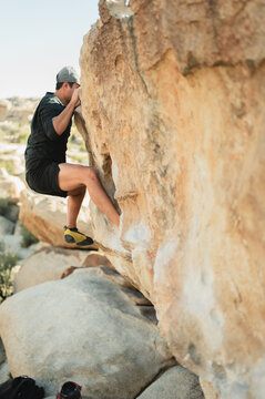 Young man bouldering on granite rock in Joshua Tree National Park