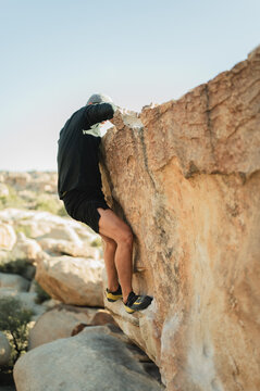 Climber topping out boulder after successful climb in Joshua Tree