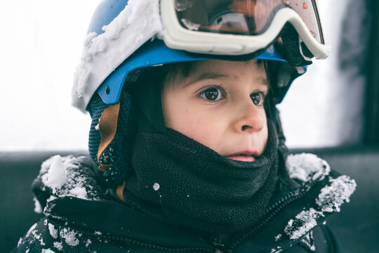 Young boy snowboarder smiles and looks out gondola window
