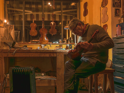 Luthier carefully varnishing scroll of violin