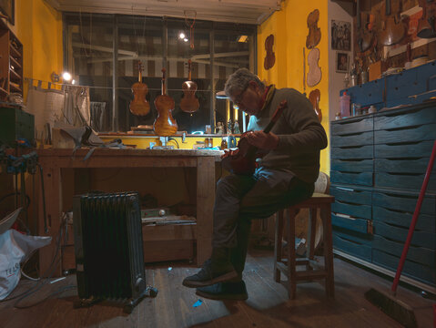 Skilled luthier varnishing the scroll of a handcrafted violin
