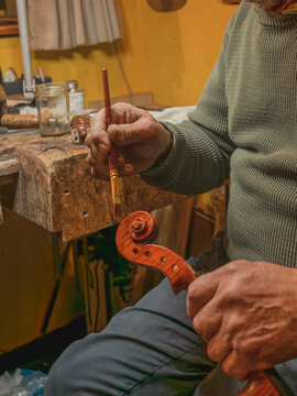 Luthier carefully varnishing violin scroll crafting