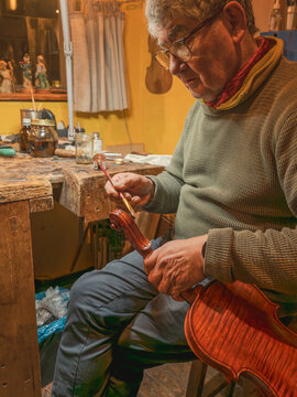 Luthier carefully varnishing violin neck