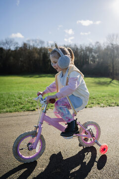 Little girl riding a pink bike in the park with her family