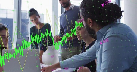 Pointing man in blue shirt reviewing charts at meeting table, laptops, chart overlay, copy space © vectorfusionart