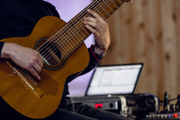 Naklejka premium Closeup photo of young man playing on electric guitar in sound recording studio Detailed view of ten-string nylon guitar during live studio performance