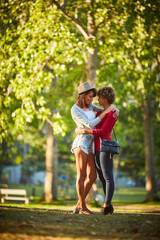 Fototapeta premium Nature, happy and lesbian couple hugging in park with bonding, love and care on vacation together. Smile, connection and lgbtq women embracing for trust in relationship outdoor on holiday with travel