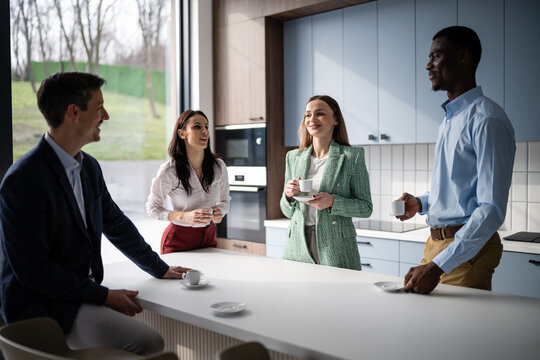 Diverse business professionals networking during coffee break in modern office kitchen