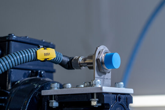 Industrial Proximity Sensor with Blue Cap Mounted on Automated Machinery