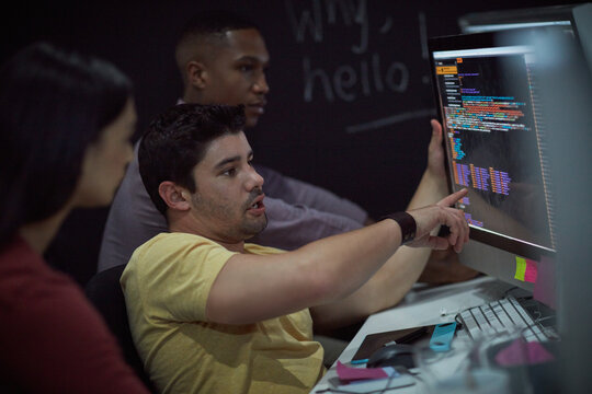 Coding, man or team with computer screen in office for software update, debugging or app testing. Night, people and pointing to tech display for problem solving, programming and database integration