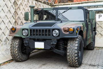 Obraz premium Military Humvee parked on an street, showcasing its rugged design and operational readiness in a secure military base. Khaki camouflage military Hummer front view. HMMWV.