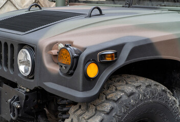 Obraz premium Military Humvee parked on an street, showcasing its rugged design and operational readiness in a secure military base. Khaki camouflage military Hummer front view. HMMWV.