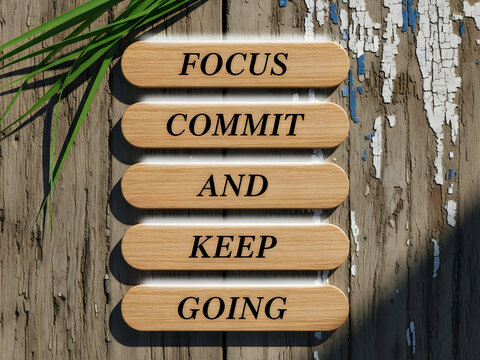 Inspirational wooden sign with focus commit and keep going on wood background