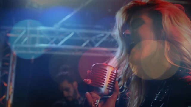 Lead singer starting singing music leaning into vintage mic as camera revealing guitar lens bokeh
