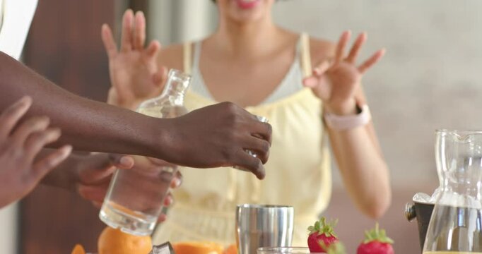 Person is aligning bottle over jigger, tilting and pouring into shaker on counter preparing drink