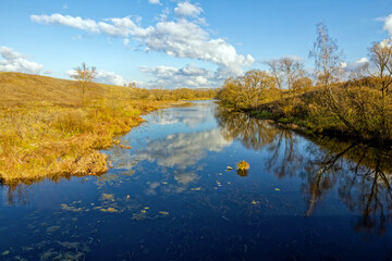 A small river near a village on a cloudy autumn day