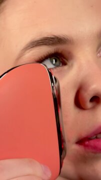 A young woman enjoys a facial massage with a microcurrent massager. Professional body treatment. Wrinkle smoothing.