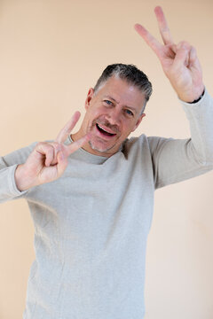 Man with gray hair and brown sweater standing in front of brown background