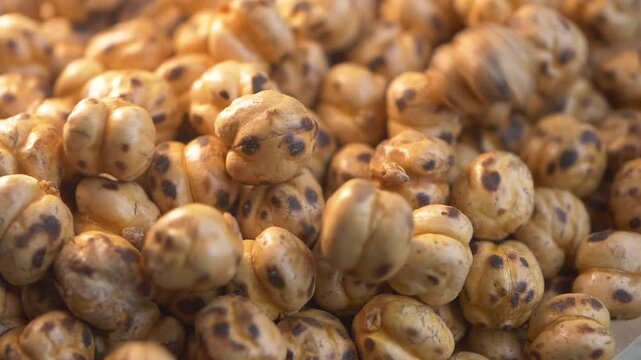 Roasted yellow chickpeas falling on stack in slow motion close up video of healthy vegan snack