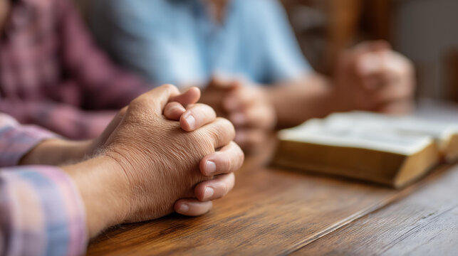 Christian worship and pray, group of people holding hands praying together, bible on wooden table devotional prayer meeting concept, faceless prayer circle, defocused background, w