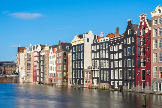 Dancing houses near river against sky, Damrak, Amsterdam, Netherlands
