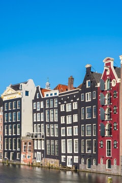 Dancing houses near river against sky, Damrak, Amsterdam, Netherlands