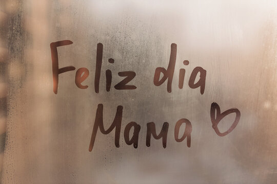 Lettering Portuguese language wish Feliz dia Mama is Happy Mother's Day in English on foggy glass wet sunset window